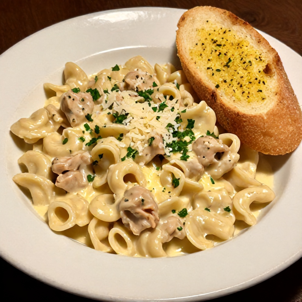 Plated serving of creamy Crockpot Chicken Tortellini with a side of garlic bread