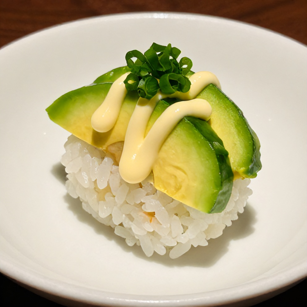 One sushi cup topped with avocado slices, julienned carrots, scallions, and a drizzle of spicy mayo on a white plate.