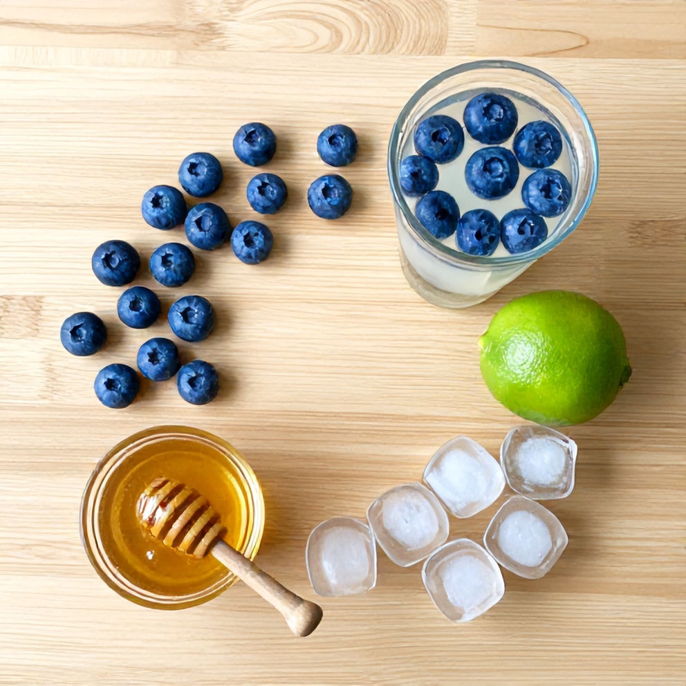 Blueberries, coconut water, lime, honey, and ice on a wooden surface