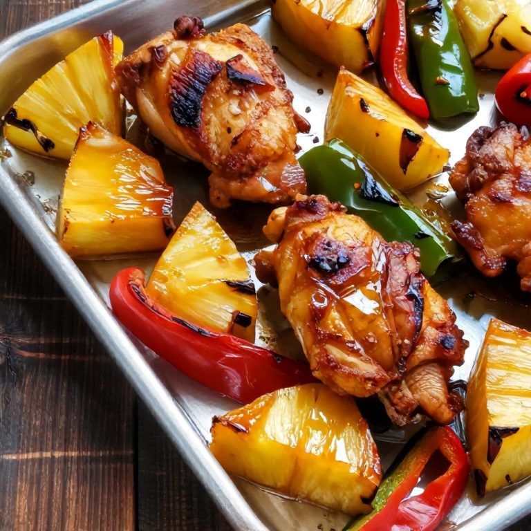 crispy golden brown hawaiian chicken with caramelized pineapple and peppers on a sheet pan with vibrant colors